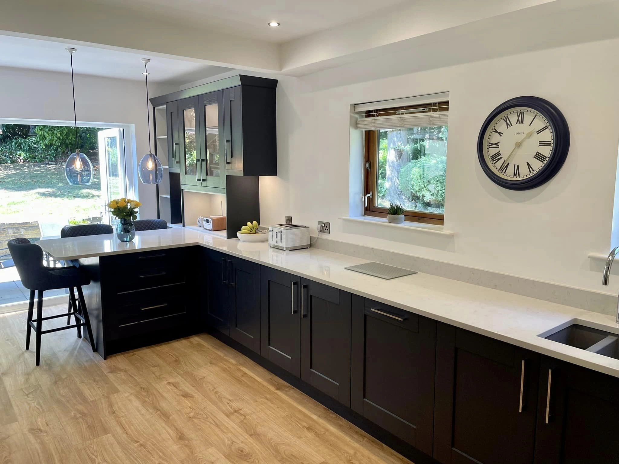 A modern looking bathroom with blue detailing, a built in breakfast bar and white worktops.
