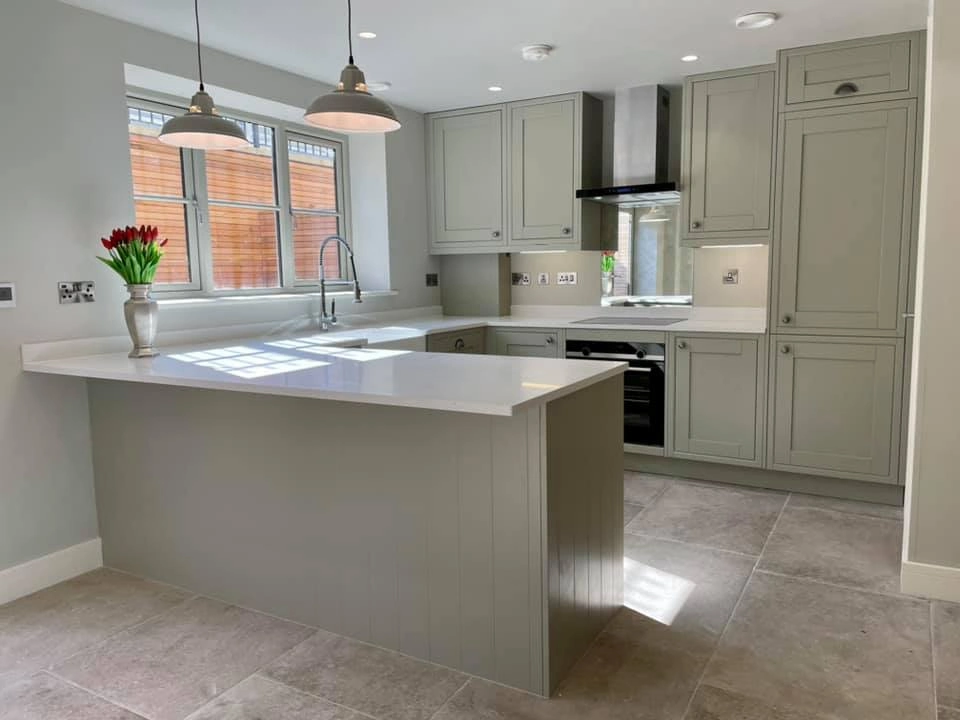 A modern looking kitchen with spotlights, embedded cupboards and fridges, and beige colours. 