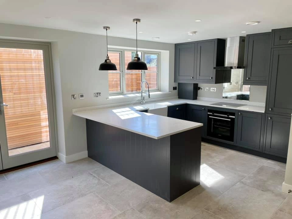 A modern looking kitchen with spotlights, embedded cupboards and fridges, and grey colours. 