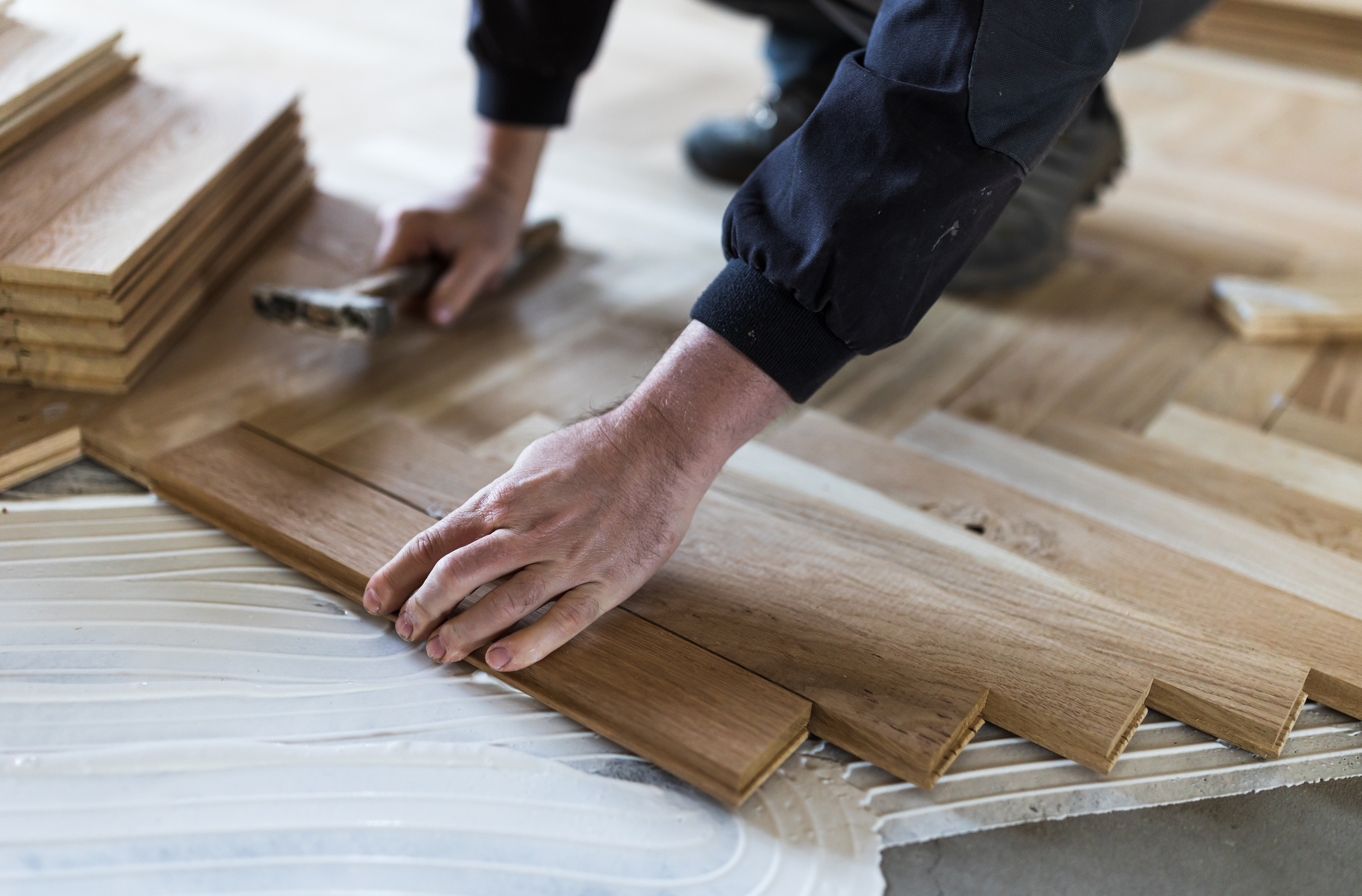 Men applying herringbone flooring to a floor, which is known to be a very achievable and easy process. 