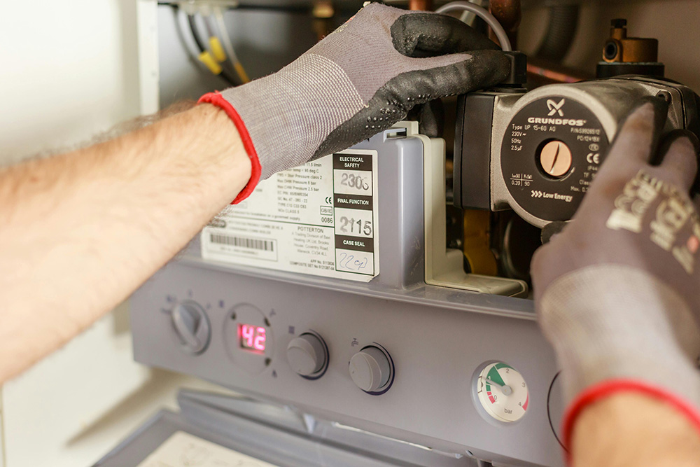 an image of a man fixing and checking a boiler within the home