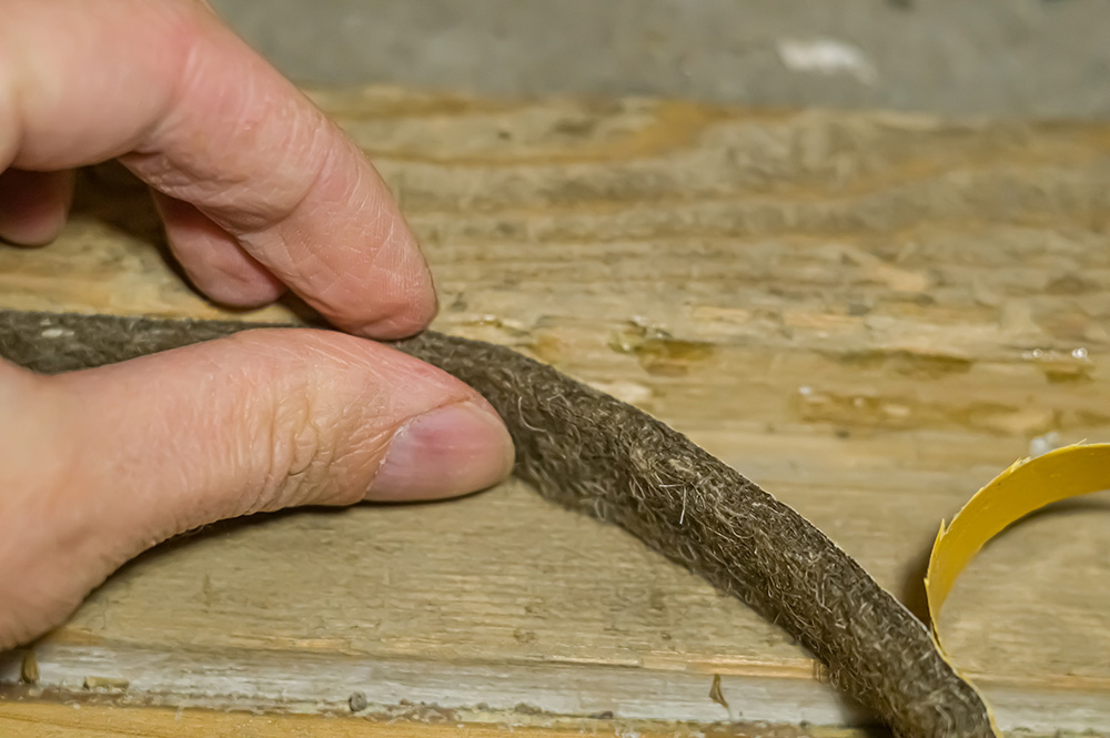 an image of a person fitting some draught proof strips to their window