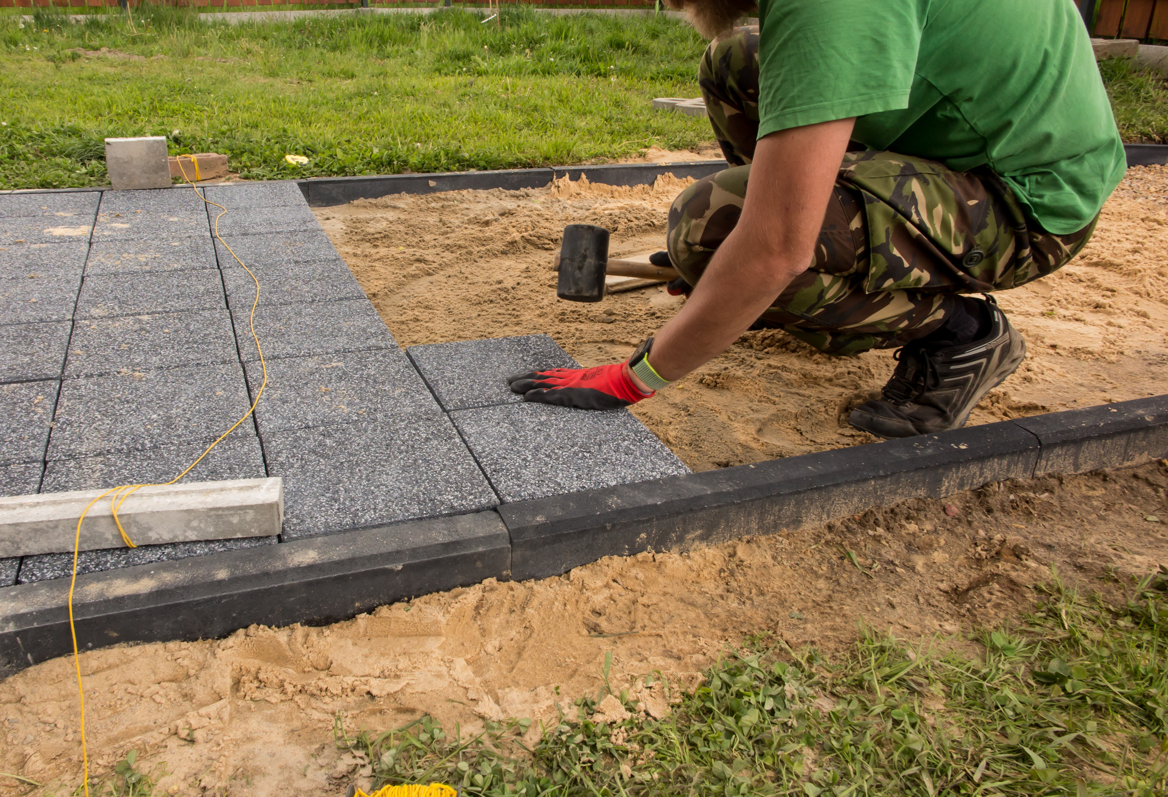 A person laying concrete paving slabs together. 