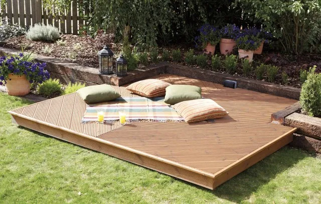 Image of composite decking with pillows and a blanket scattered all over it.