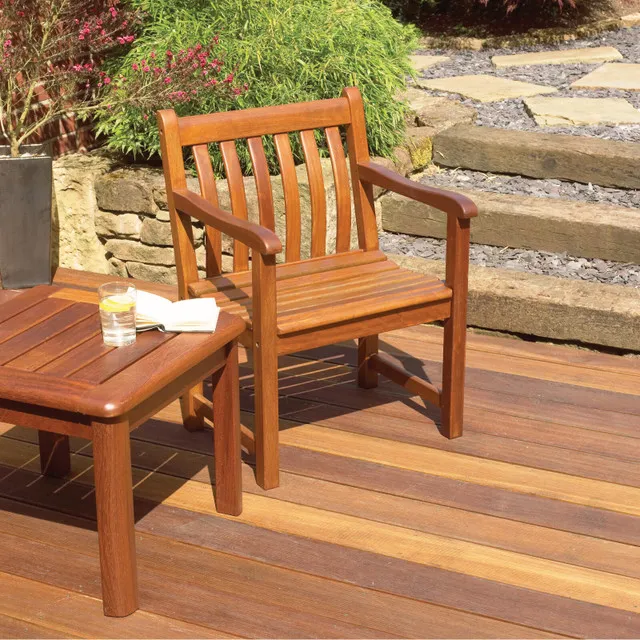 Image of a garden chair made of timber on some decking outside, sat next to a timber table.