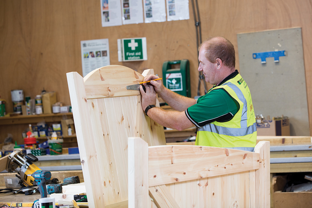 an image of a man measuring the distance between two wooden gate beams