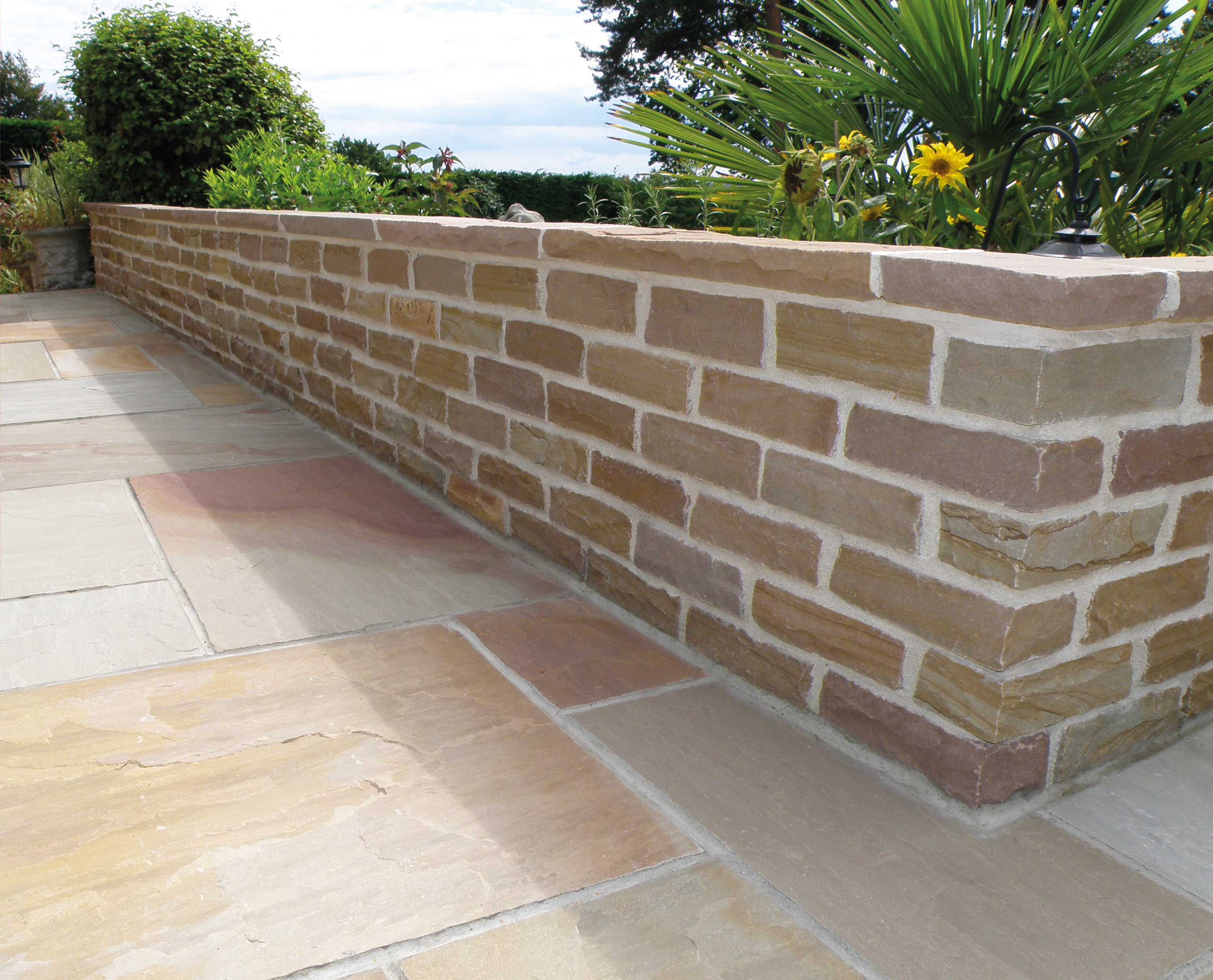 Paving slabs in a nice garden with small wall.