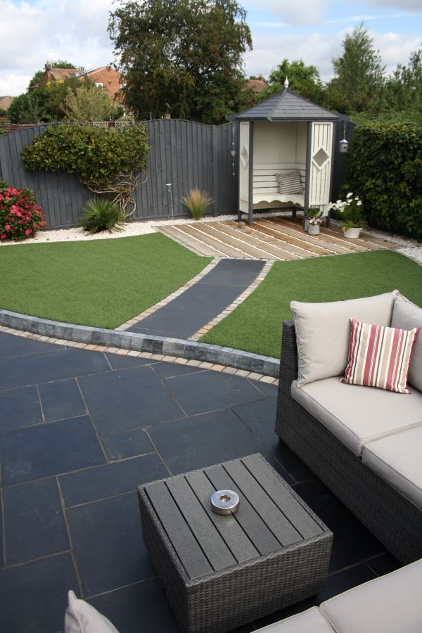 A landscape picture of garden furniture on top of a patio in the garden. 