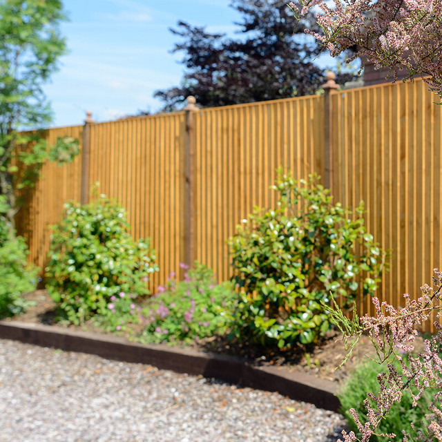A nice brown fence and shed being used in a garden to display sections of the landscape. 