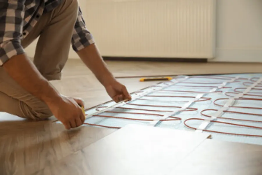A man applying some underfloor heating beneath some flooring.