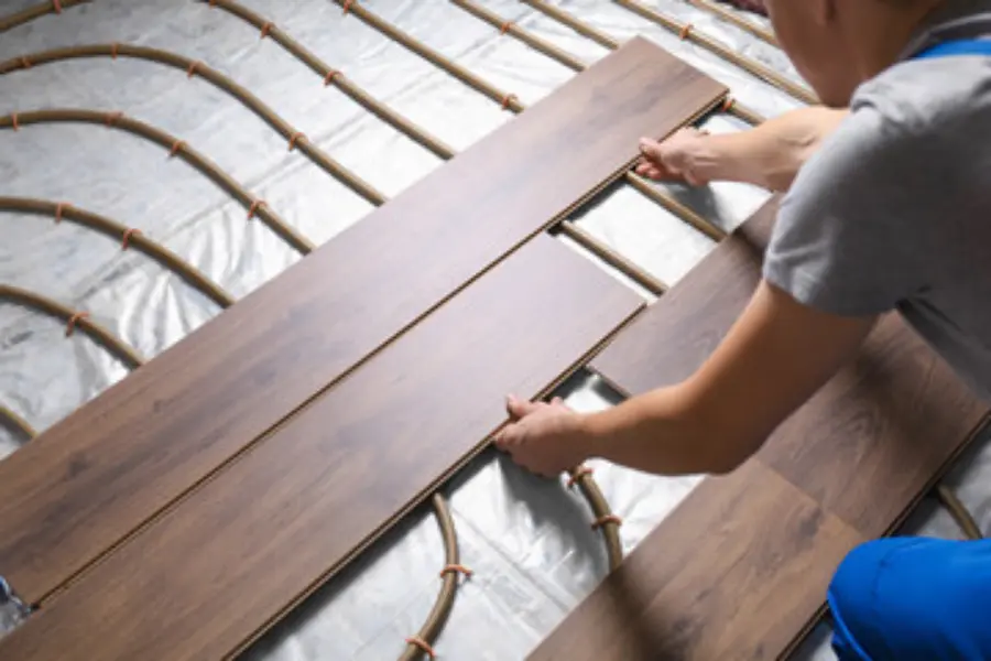 Man laying flooring down above underfloor heating, which can be applied in many areas of the home.