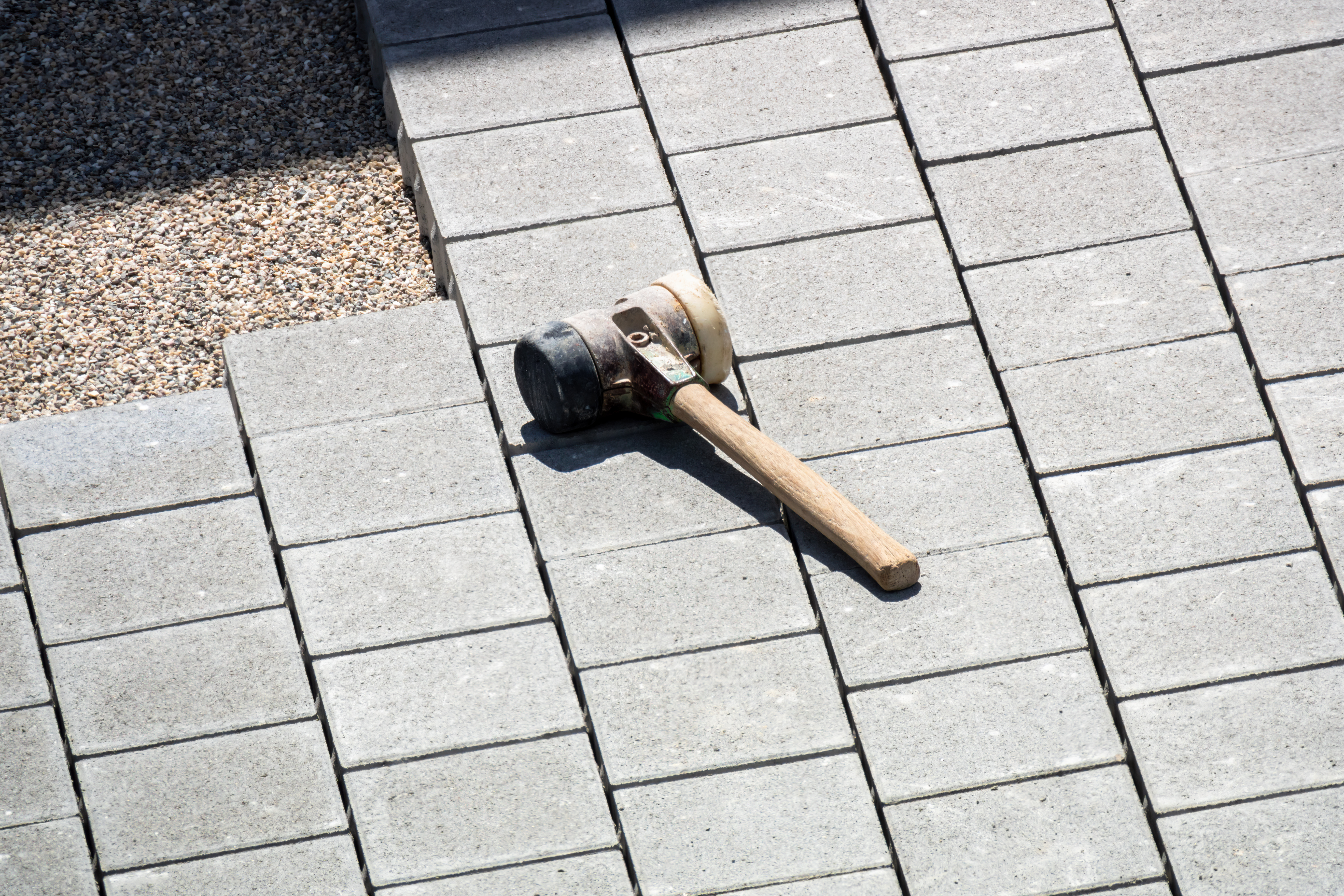 A club mallet on top of concrete paving slabs on top of a sub base for a patio.