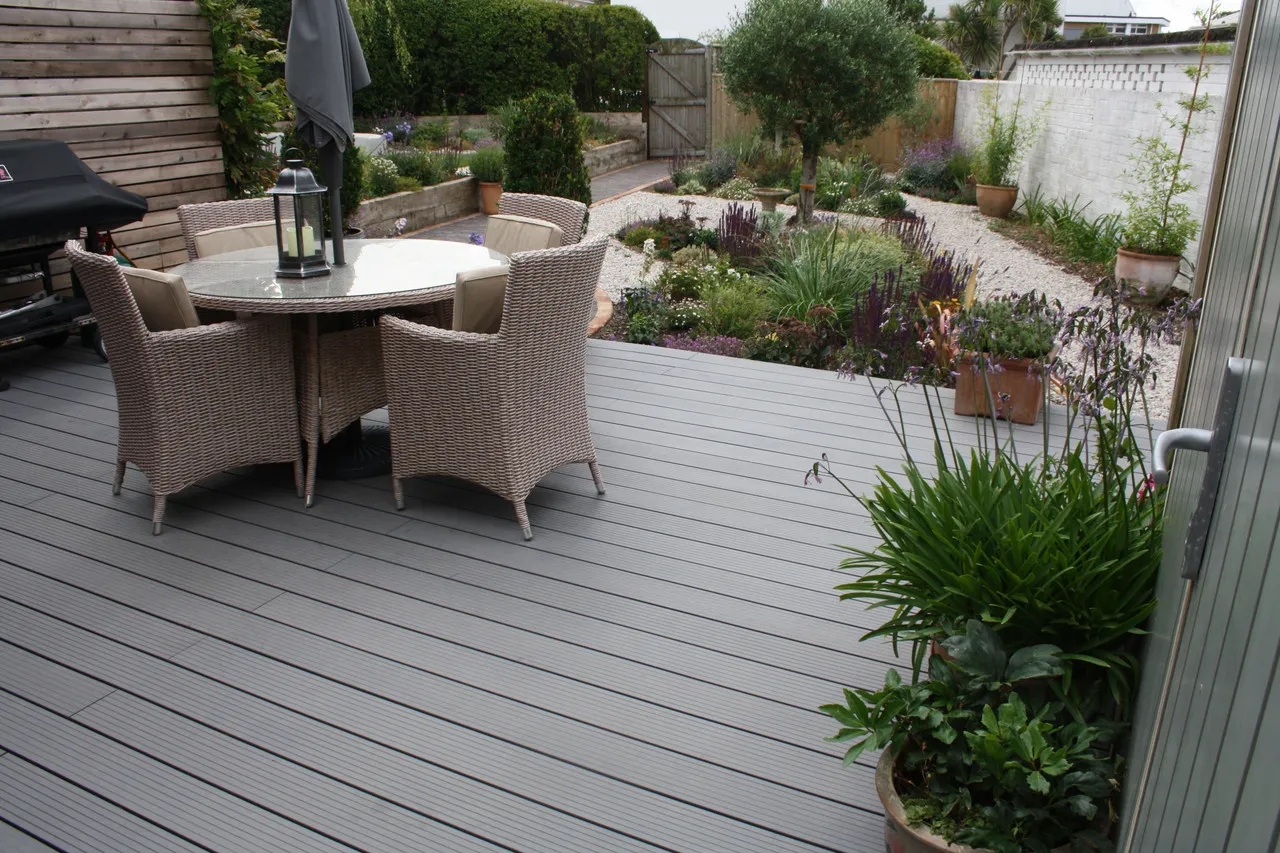 A lifestyle shot of some decking outside a person's house, with furniture and plants surrounding it.