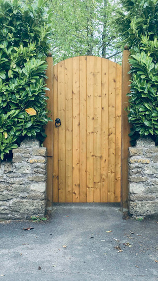 an image of a white garden gate outside a cottage home, with a lime door