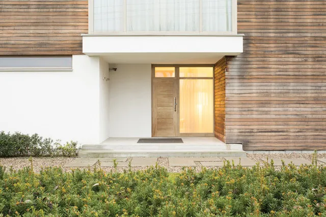 A far-away image of a door leading into a white modern home.