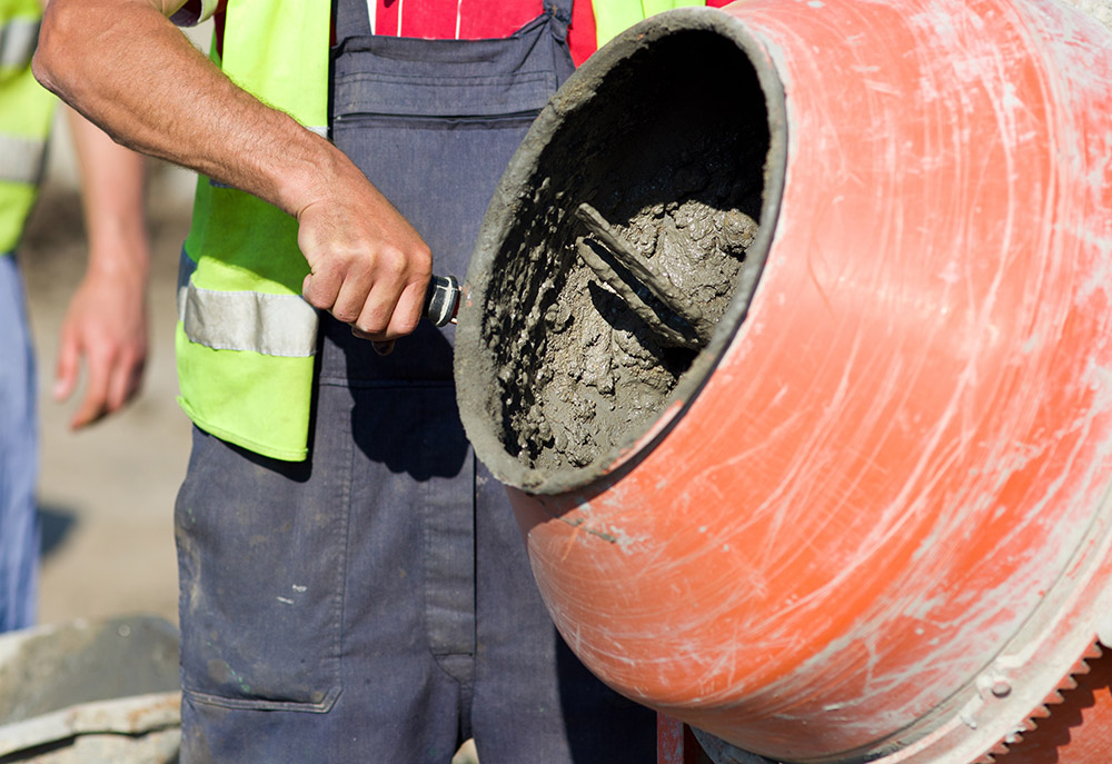 an image of a man putting cement mix in mixer