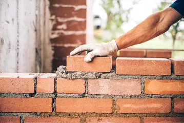 Bricks being pressed together with mortar by a builder.