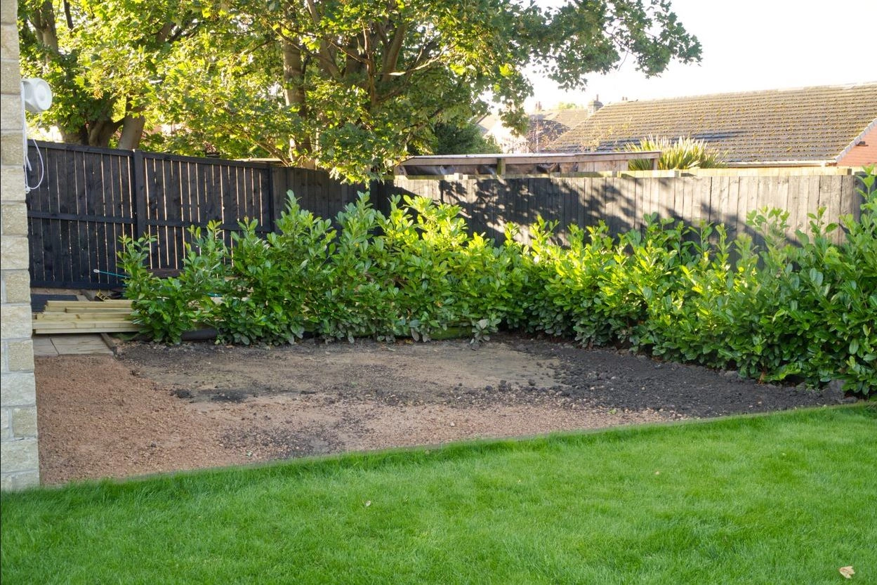 A landscape picture of an empty back garden which has been dug out for a deck to be installed.