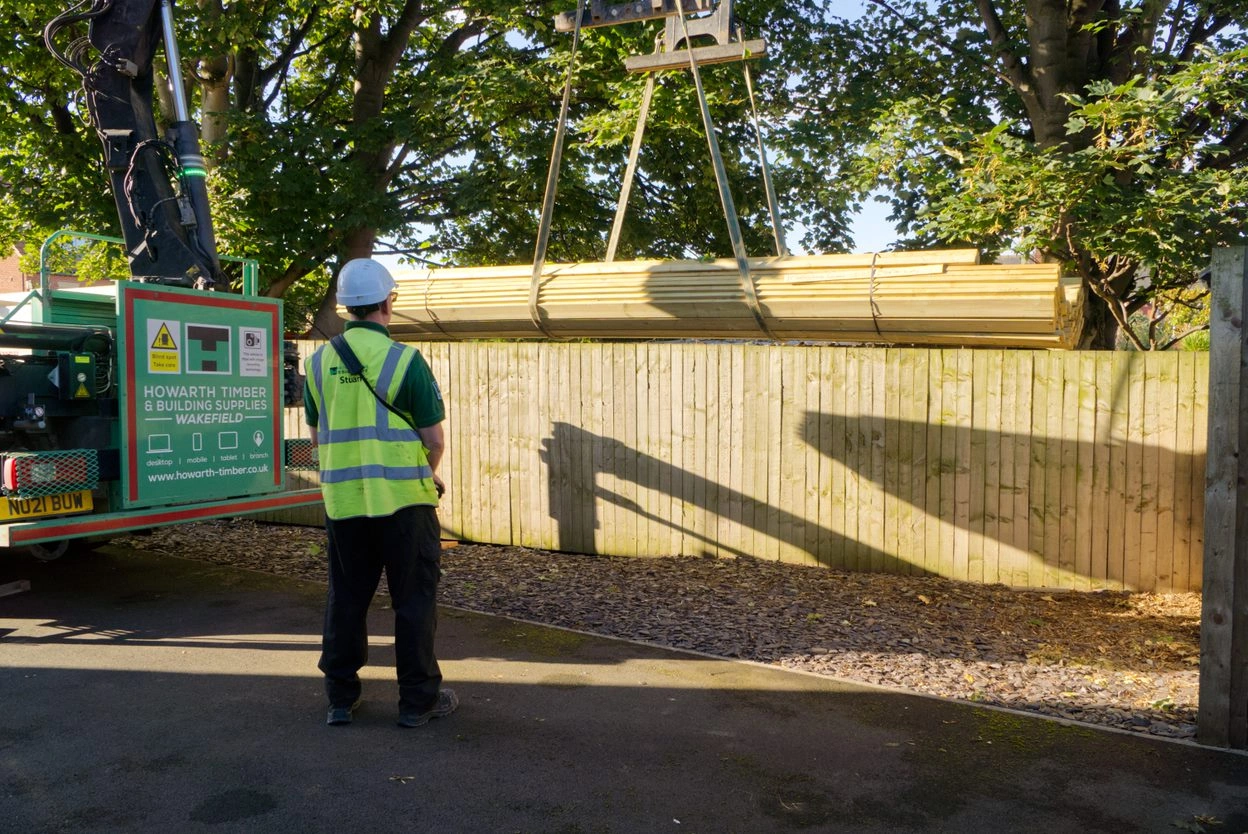 A man over seeing the delivery process of the decking materials being delivered to a customers home.