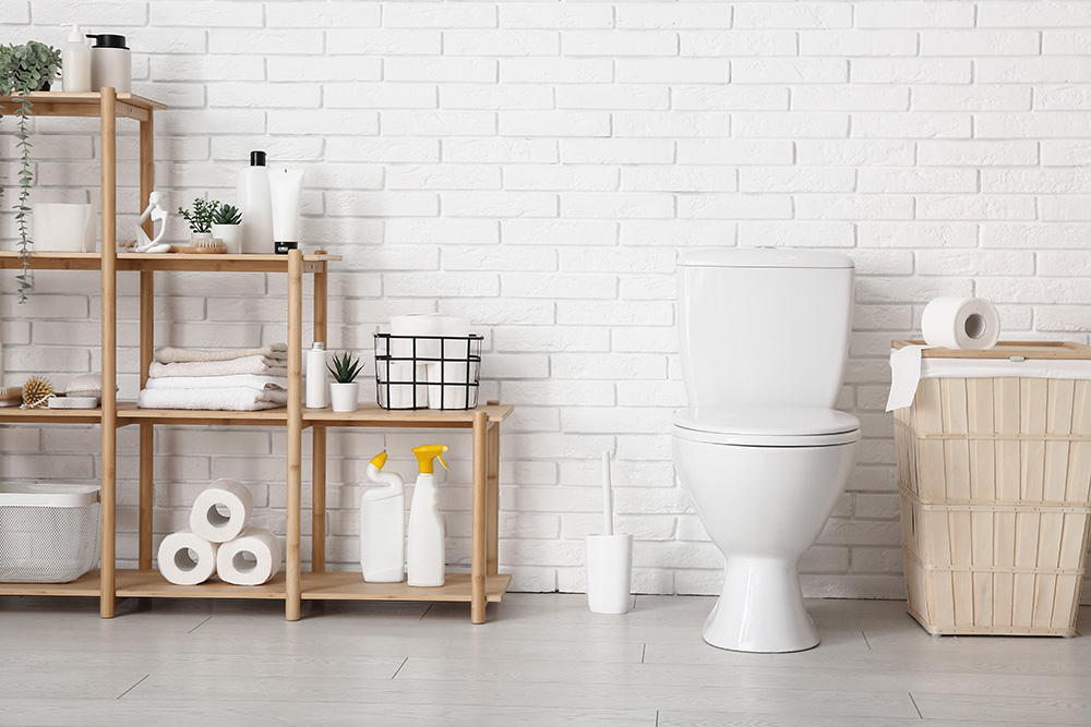 A toilet in an outside space against a bright blue wall with a sink and some decorations.