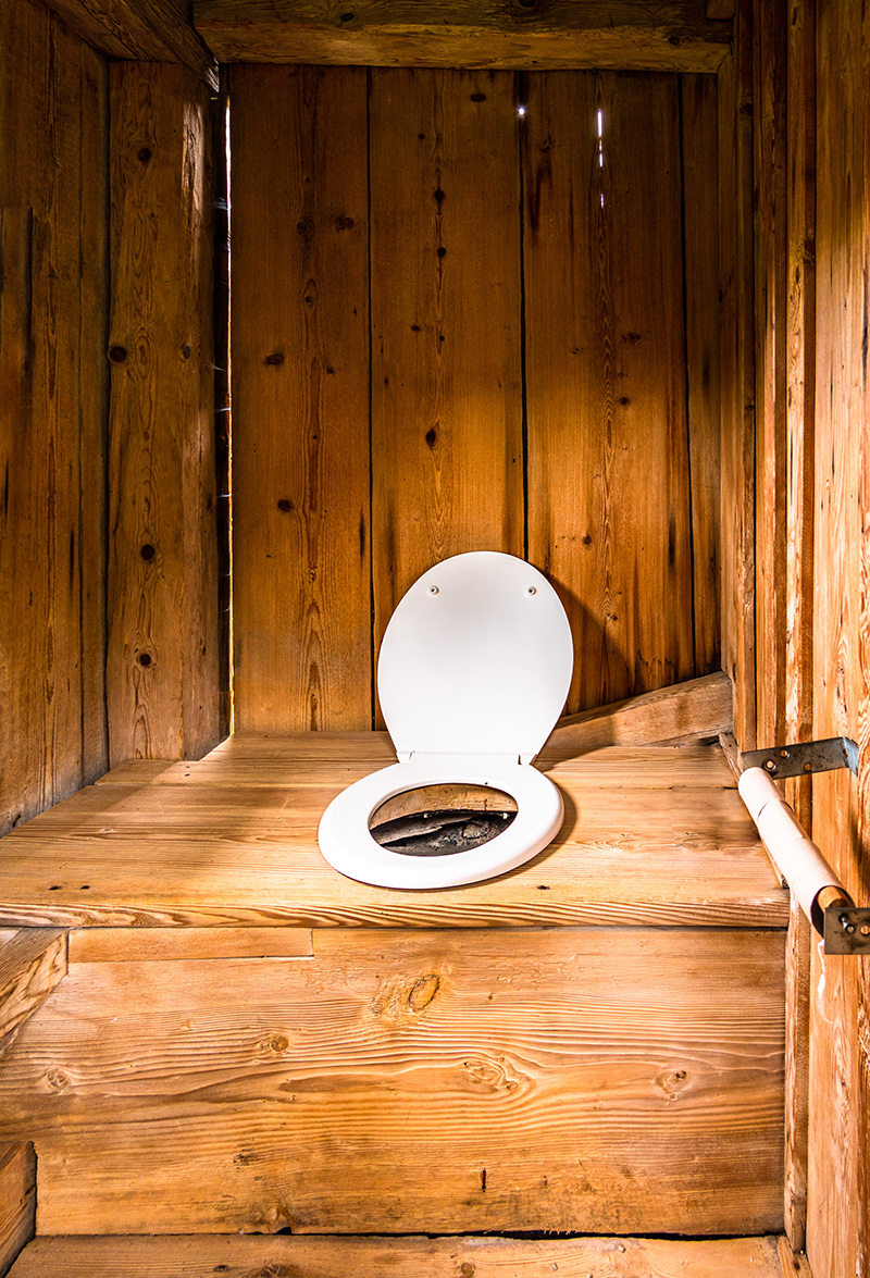 An outside timber wooden cabin made to be an outside toilet for guests.