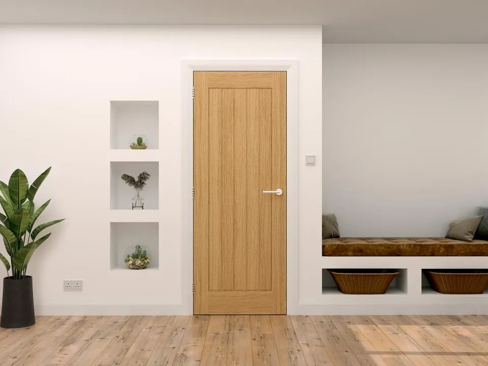 An oak internal door in a home, along white, bright walls.