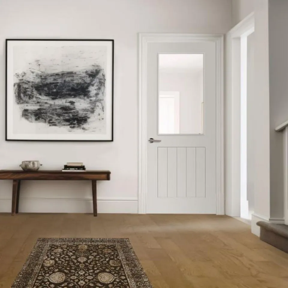 A white, glass panel internal door in a modern, white-walled home.