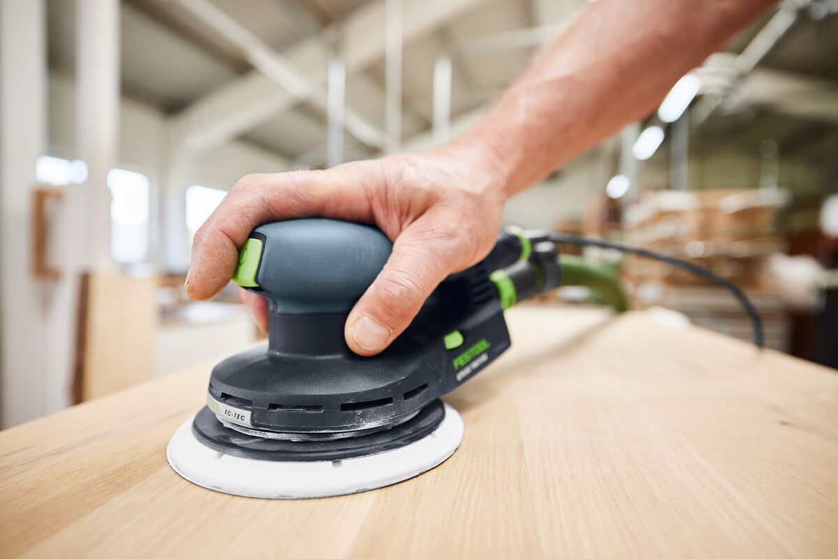 Handwerker schleift eine flache Holzplatte mit dem ergonomischen Festool Exzenterschleifer ETS EC 150