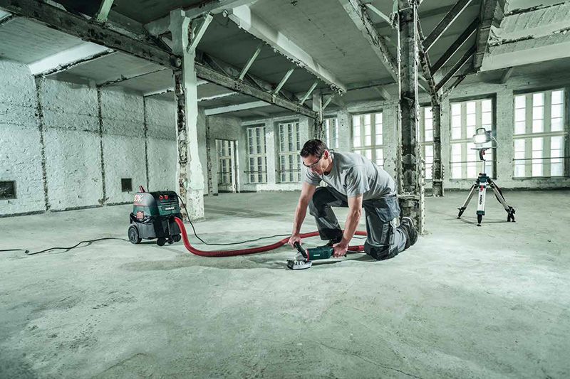 Handwerker schleift einen Boden mit angeschlossenem Metabo Bau-Entstauber
