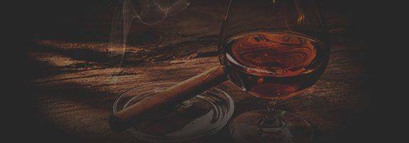 glass of whisky and cigar on table