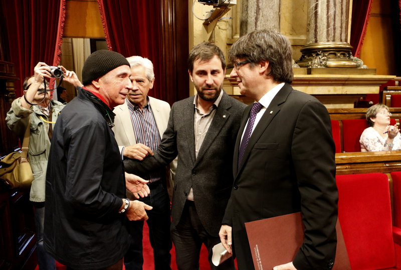 El president de la Generalitat, Carles Puigdemont, saluda el diputat de JxSí Lluís Llach, al ple del Parlament del 26 d'abril de 2017. (Horitzontal)