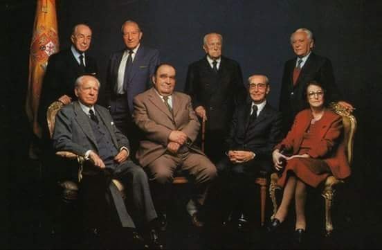"Fotografía de Alberto Schommer (1987) publicada en El País Semanal. De pie, de izquierda a derecha: José María Aguirre Gonzalo, empresario y banquero; Ramón Rubial, Presidente del PSOE; Raimundo Fernández Cuesta, Secretario General de Falange Española; Ignacio Gallego, Juventudes socialistas Unificadas y Partido Comunista de España. Sentados, de izquierda a derecha: Ramón Serrano Suñer, CEDA y Ministro de Exteriores de Franco; Enrique Líster, Partido Comunista de España, jefe del V Regimiento; Jesús María Leizaola, PNV, Consejero del Gobierno de José Antonio Aguirre y Lendakari; Pilar Primo de Rivera, Jefe de la Sección Femenina de Falange Española.