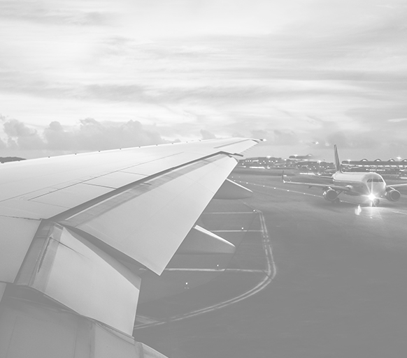 View over right airplane wing, airplane static and parked in airfield.