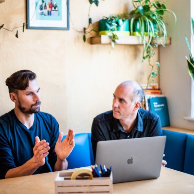 Two men around a table discussing client work