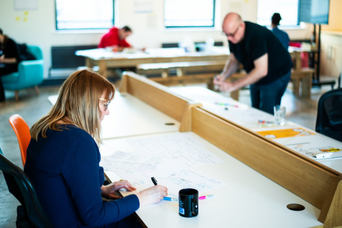 Four people working through design sprint exercises at desks