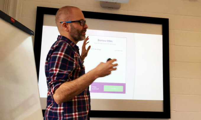 A man presenting a design prototype for Suffolk libraries on a big screen