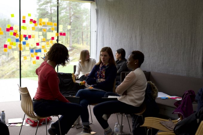 Group sat in front of a glass wall of post-its talking