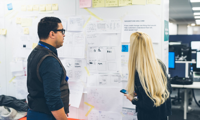 Man and woman looking at office wall with design sketches