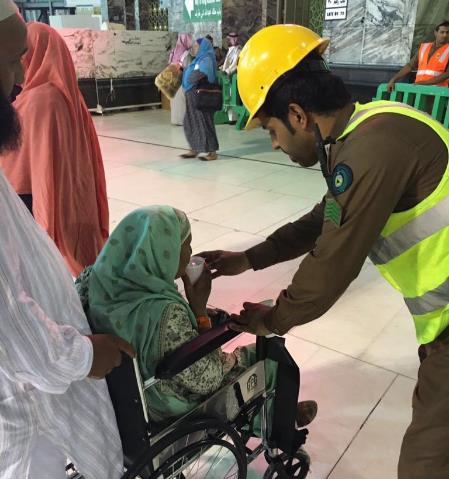 رجل أمن يسقي معتمرة مسنة رجل أمن يسقي معتمرة مسنة