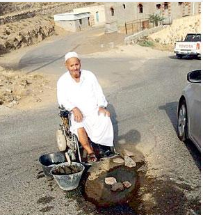 مسن مقعد يردم حفرة تتوسط شارعا في المجاردة