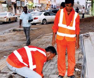 عاملان يركبان اغطية الصرف الصحي