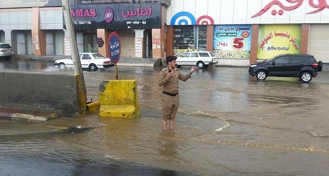 ضابطا مرور يشمّران عن ساقيهما لتنظيم المركبات في طريق مليء بالمياه 