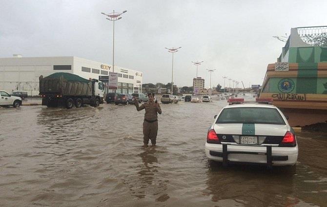 ضابطا مرور يشمّران عن ساقيهما لتنظيم المركبات في طريق مليء بالمياه 