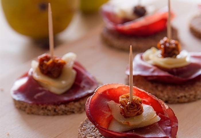 Crostini di pane nero, bresaola, pera e bacche di Physalis