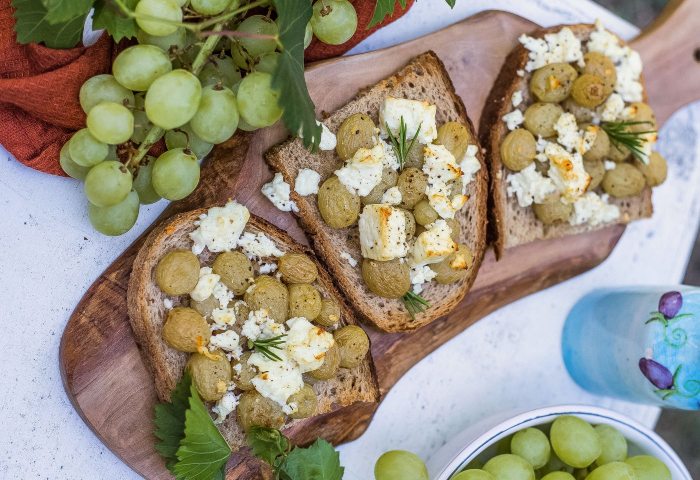 Crostoni di pane integrale con uva al forno, feta e miele