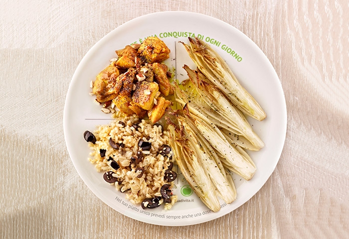 Piatto unico con indivia al forno, pollo al curry e mandorle, riso alle olive