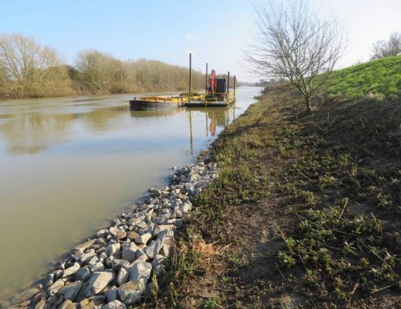 A close up of stone that has been placed at the bottom of an embankment.