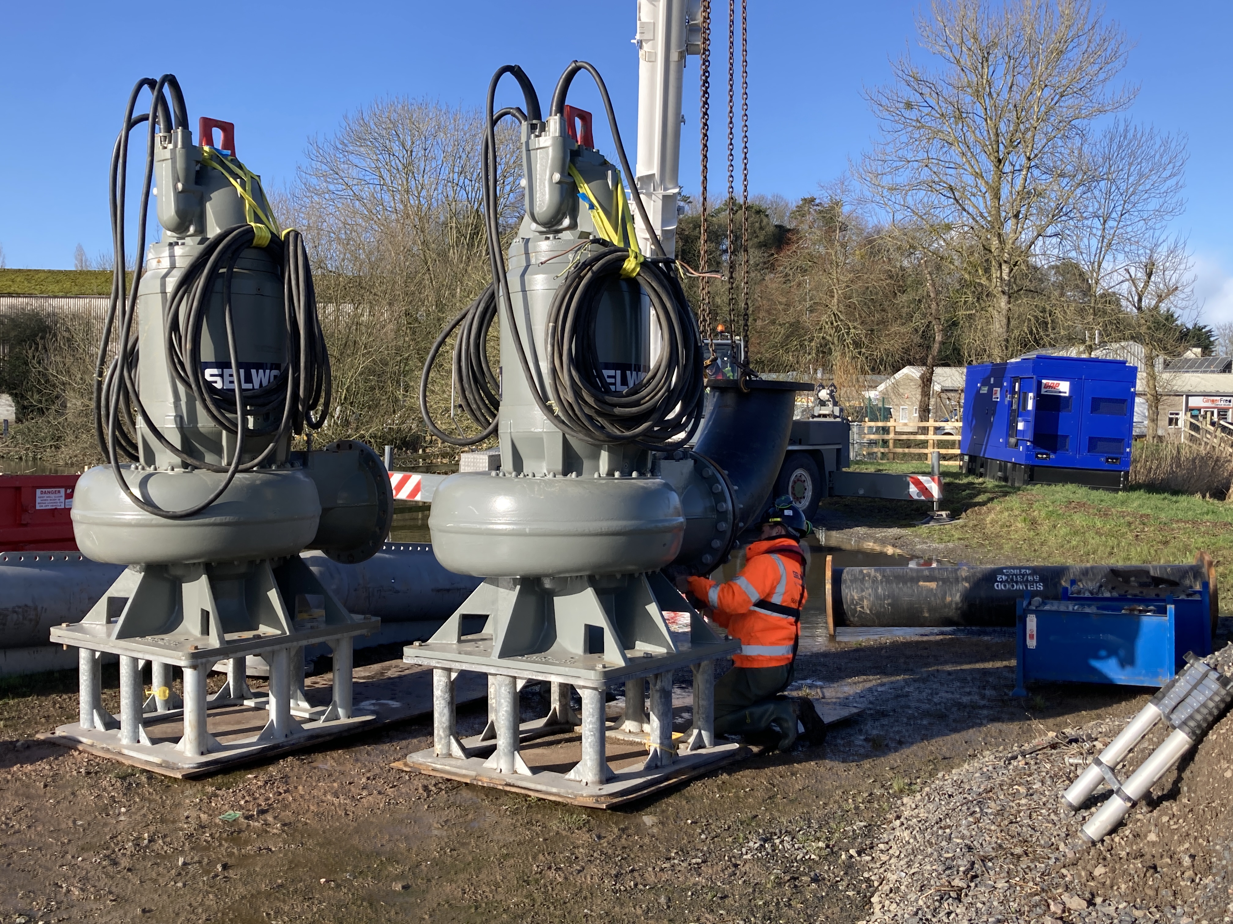 Staff on the ground preparing large grey pumps 