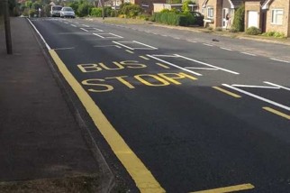 Image shows a yellow bus stop marking painted on a residential street