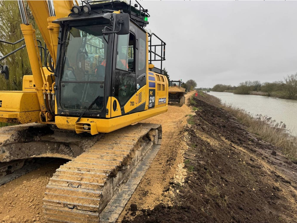 Close up of a 360 digger on top of a river embankment.